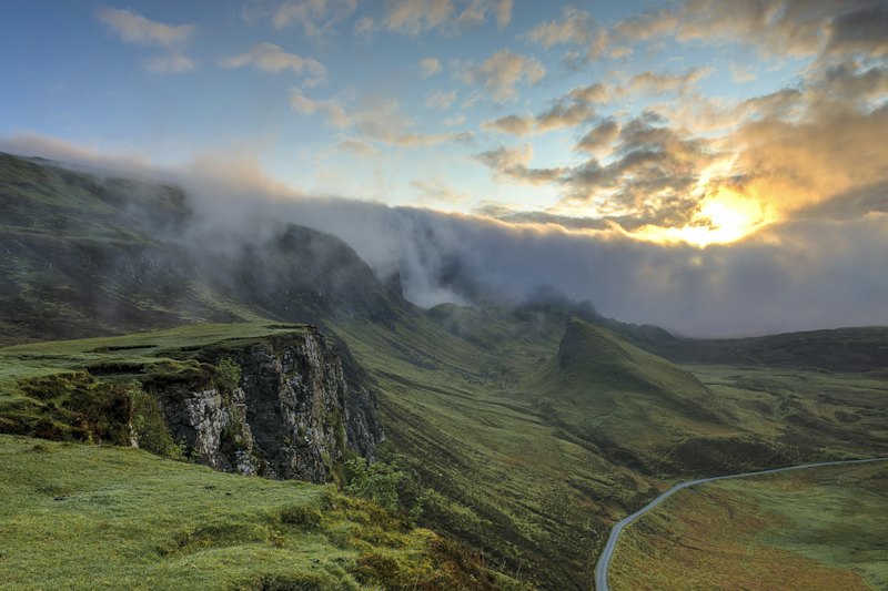Mist rolling over green cliffs at sunrise