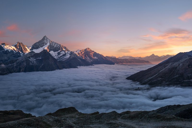 Mountain peaks rising above a sea of clouds at dusk