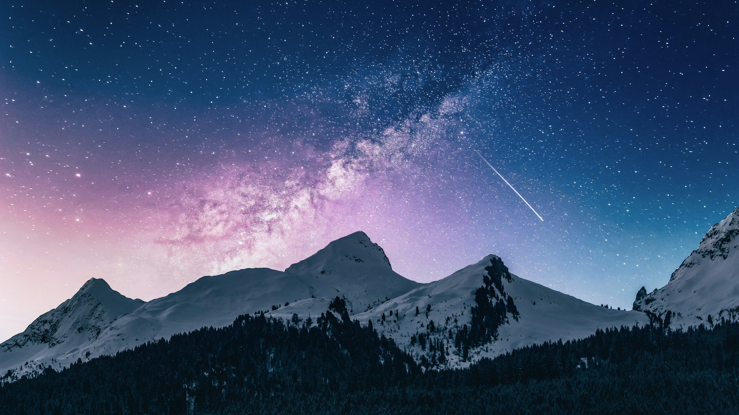Snow-capped mountains under a purple night sky and the Milky Way